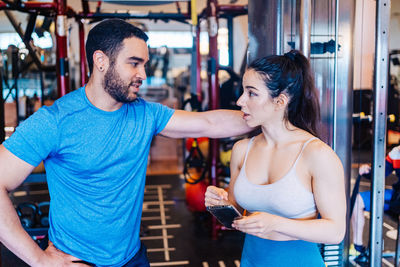 Full length of man and woman standing in gym taking a break from exercising 