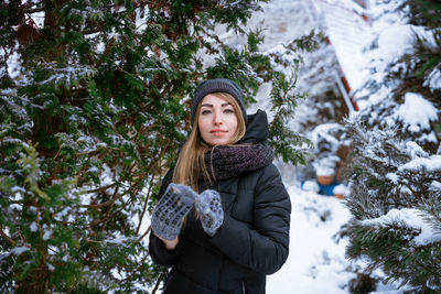 Portrait of young woman standing against trees