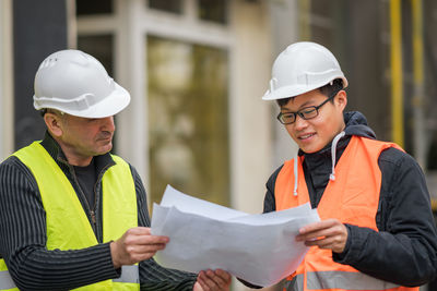 Engineers discussing while standing at construction site