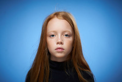 Close-up of young woman against blue background