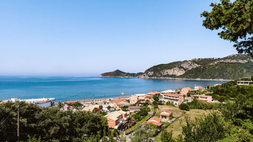 Scenic view of sea by buildings against clear blue sky