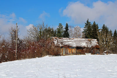 House on snow covered field against sky