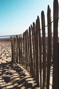 Wooden posts on beach against clear sky