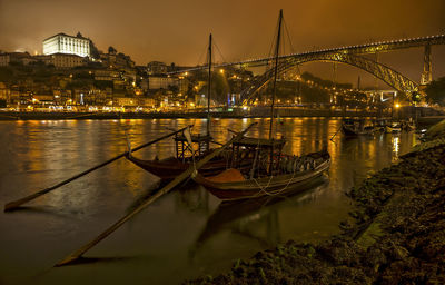 Illuminated bridge over river in city at night