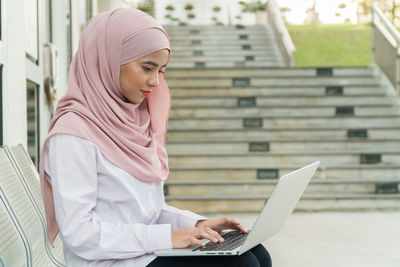 Young woman using laptop while sitting on seat