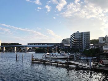 Pier over river by buildings in city against sky