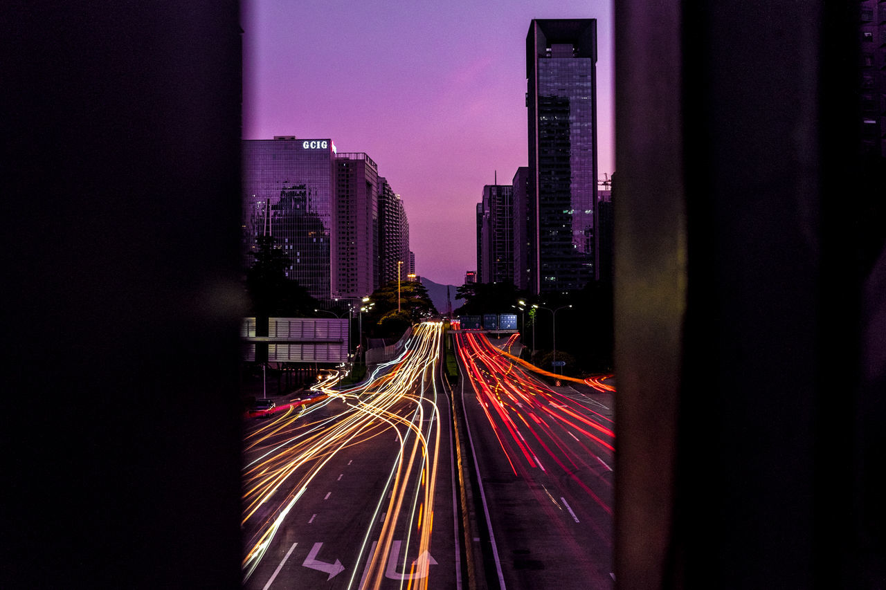 long exposure, speed, light trail, illuminated, transportation, motion, building exterior, architecture, built structure, night, tower, road, city, sky, skyscraper, outdoors, vanishing point, tall - high, development, modern, urban skyline, tail light, diminishing perspective, tall