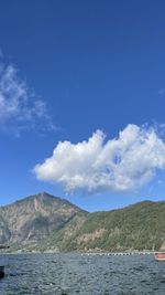Scenic view of sea by mountains against blue sky