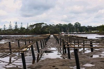 Pier on sea against cloudy sky