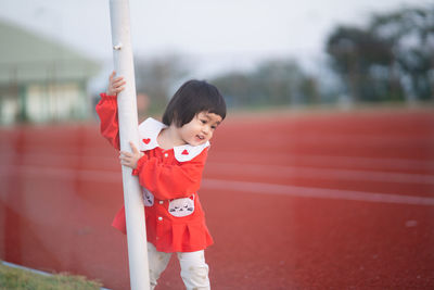 Cute girl holding pole standing by running track