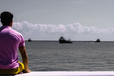 Rear view of man standing on sea against sky