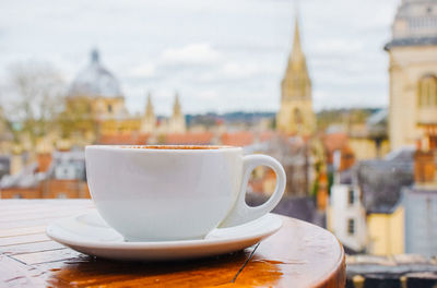 Close-up of cup on table against buildings in city