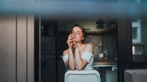 Portrait of young woman looking away at home