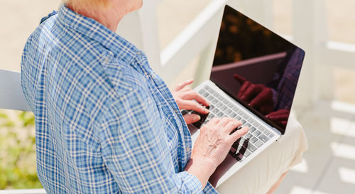 Unrecognizable senior woman using laptop for distance education outdoors