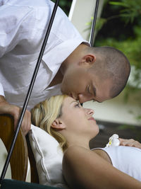 Close-up of boyfriend kissing girlfriend lying on swing