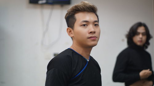 Portrait of young man standing against wall