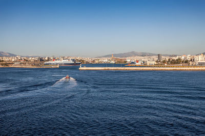 Scenic view of sea and buildings against clear blue sky