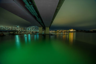 Illuminated bridge over river against sky at night