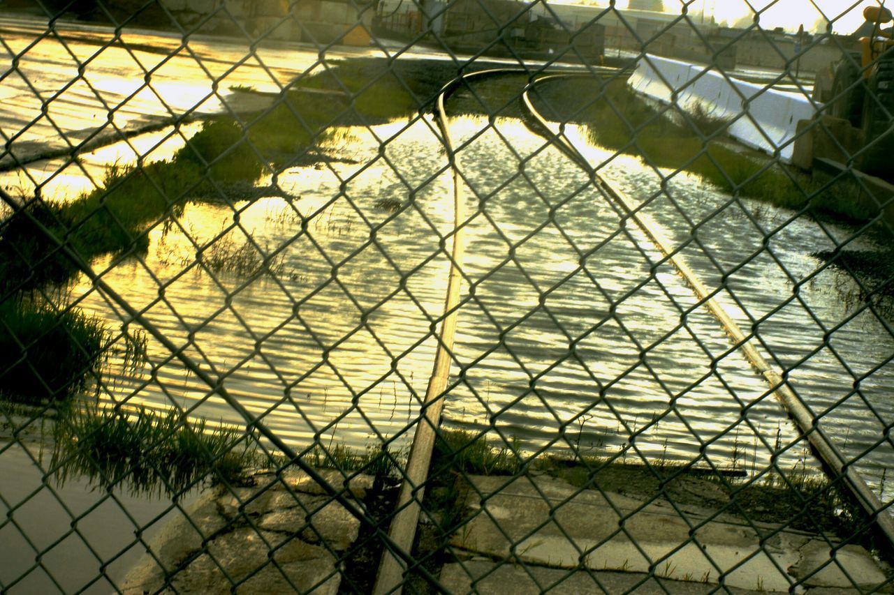 chainlink fence, fence, protection, metal, safety, pattern, sunlight, security, shadow, tree, railing, no people, gate, metallic, built structure, day, grass, outdoors, park - man made space, footpath