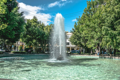 Fountain in park against cloudy sky