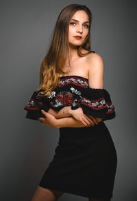 Portrait of beautiful young woman standing against gray background