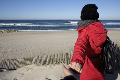 Cropped image of man holding woman hand at beach against sky