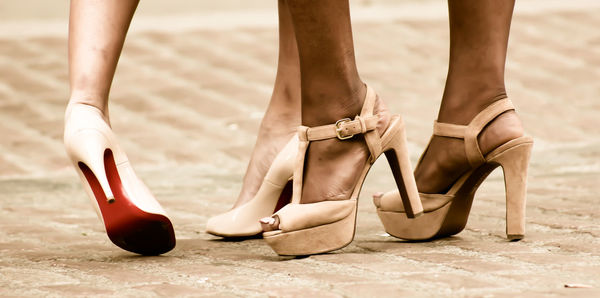 Low section of women in high heels walking on footpath