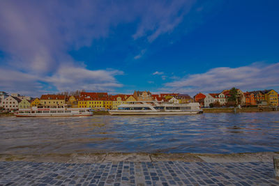 View of river by buildings against blue sky