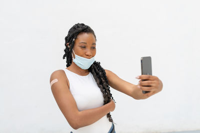 Young woman using mobile phone against white background