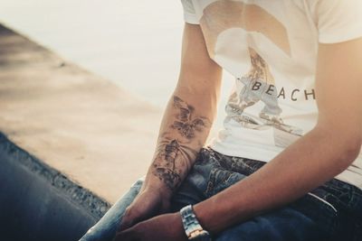 Midsection of man sitting on retaining wall