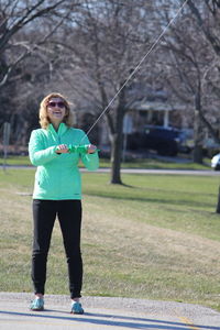 Smiling woman flying kite on footpath in park