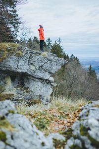 Side view of mature woman standing on rock against cloudy sky