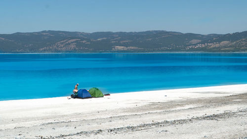 Mid distance view of man standing by tent on shore at beach