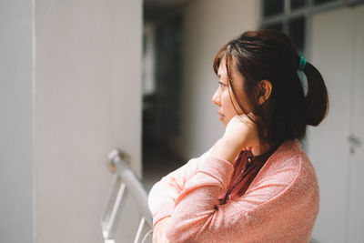 Thoughtful woman at railing in corridor looking away