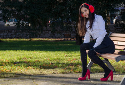 Portrait of smiling young woman sitting on park bench