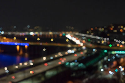 Defocused image of illuminated city against sky at night