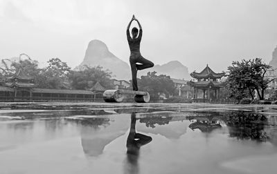 Rear view full length of woman doing yoga by puddle