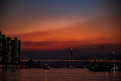 Illuminated bridge over river against sky during sunset