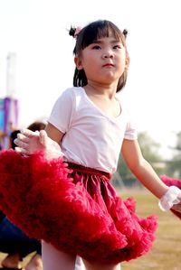 Cute girl holding pink while standing outdoors