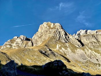 Low angle view of snowcapped mountain against blue sky