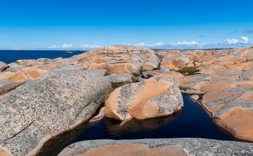 Rocks by sea against blue sky