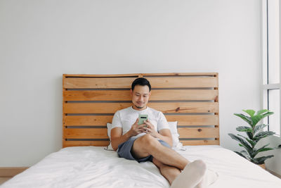 Woman sitting on bed at home