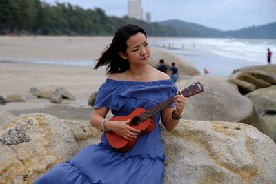 Young woman playing guitar at beach