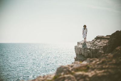 Woman standing by sea on rock