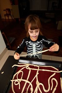Boy child in skeleton costume preparing for halloween holiday