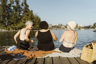 Side view of woman sitting on pier against lake