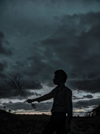 Side view of silhouette man standing on field against sky
