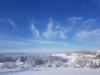 Scenic view of snow covered landscape against blue sky