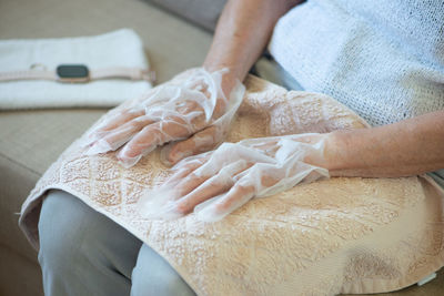 Senior woman wearing hand mask gloves. moisturising gloves to soften hand skin. hands close up.