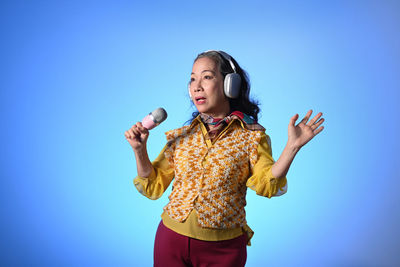 Portrait of young man standing against blue background